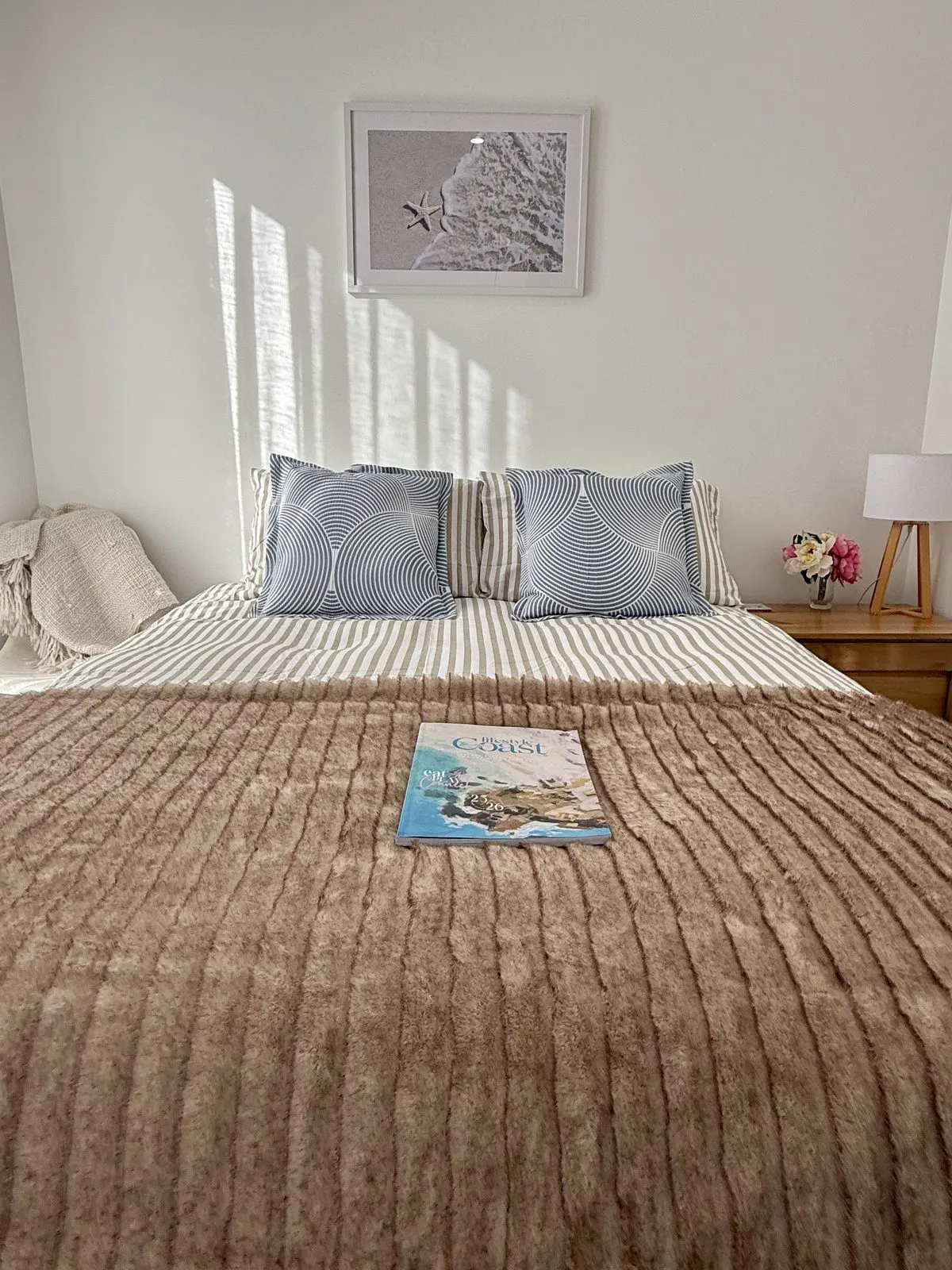 Queen bedroom with coastal artwork and morning light at Drift