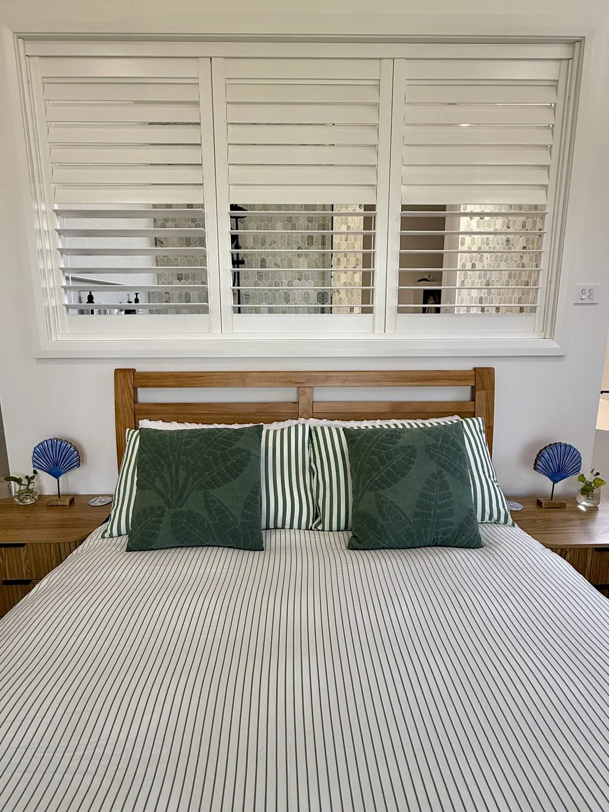Master bedroom with plantation shutters opening to ensuite at Drift, Tea Gardens