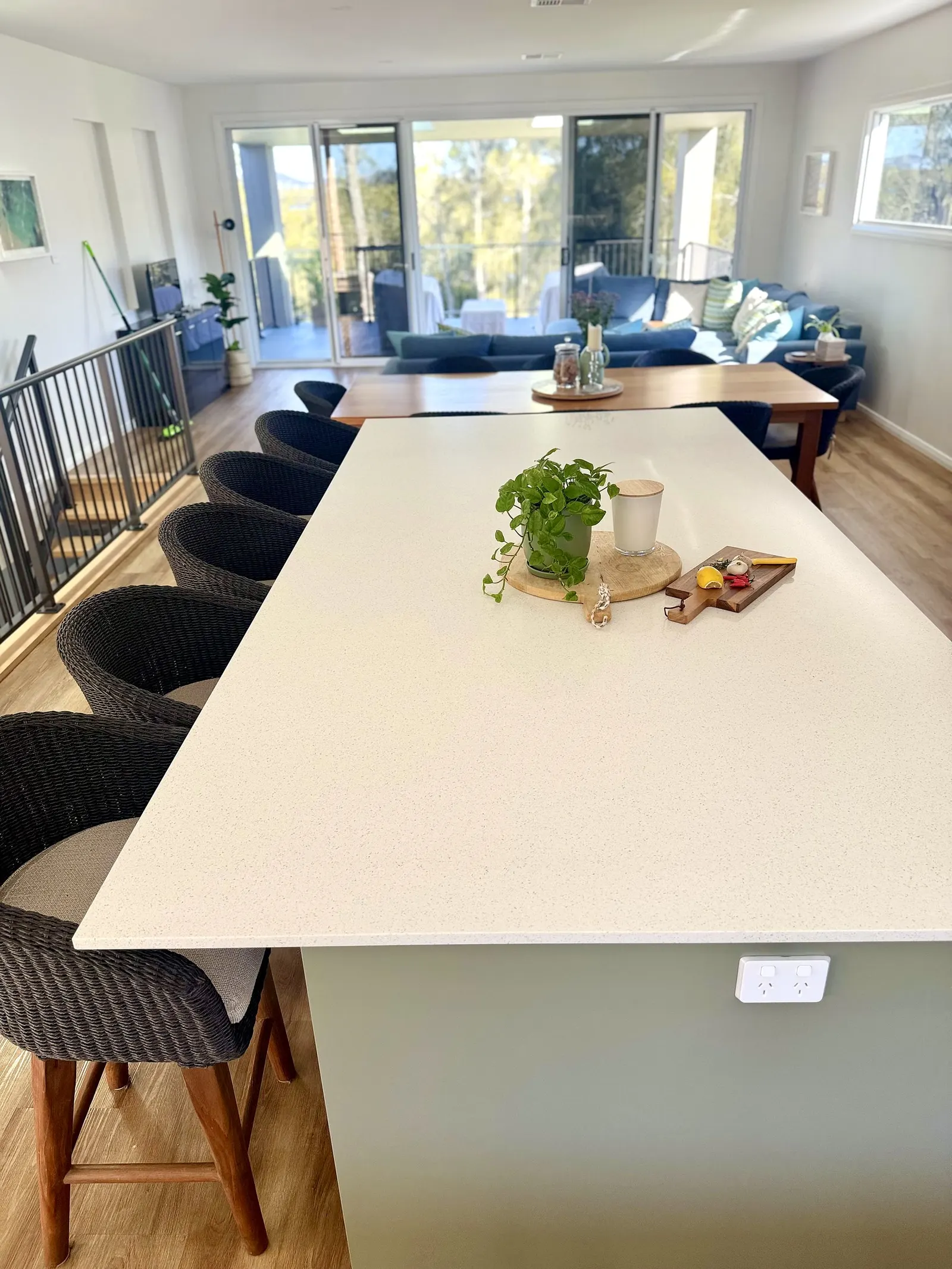 Styled kitchen island bench with dining and living area beyond at Drift