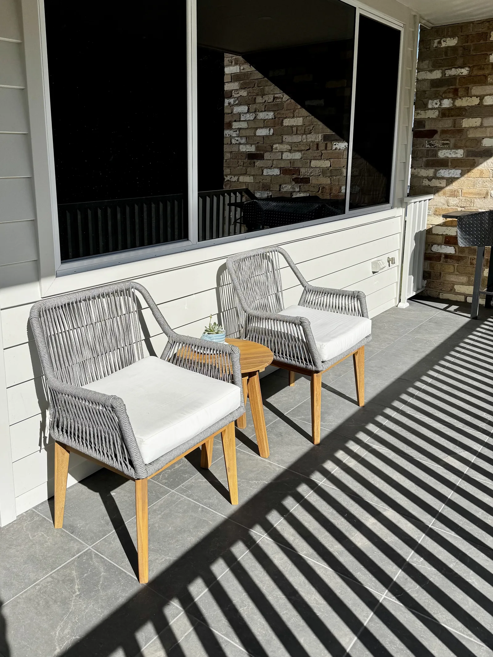 The BBQ Balcony — sunny street-side balcony with chairs and the barbecue, next to the kitchen at Drift, Tea Gardens