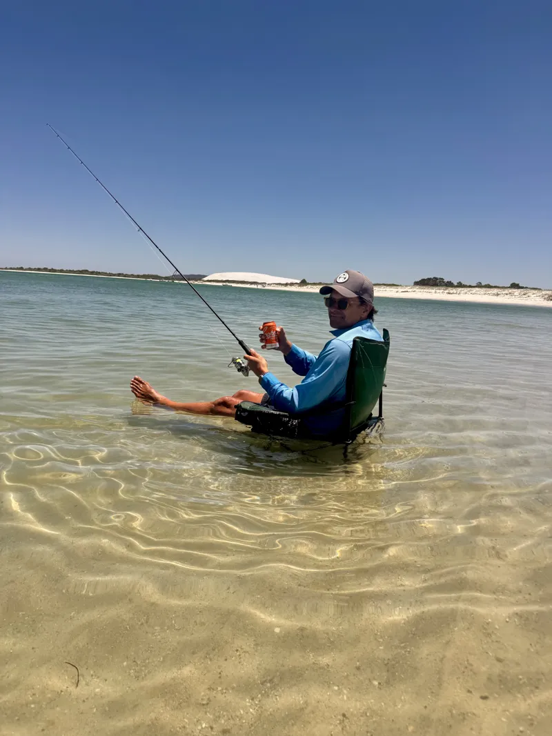 Matt fishing from a camp chair in shallow, clear water